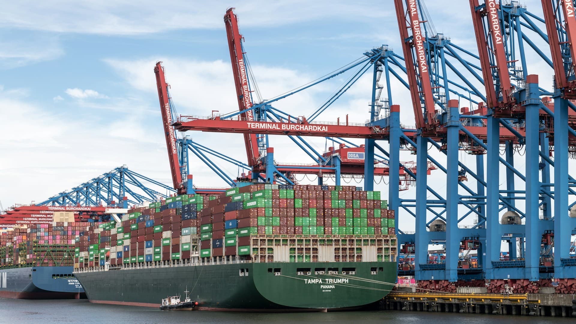 Container ship docked at a busy port with cranes